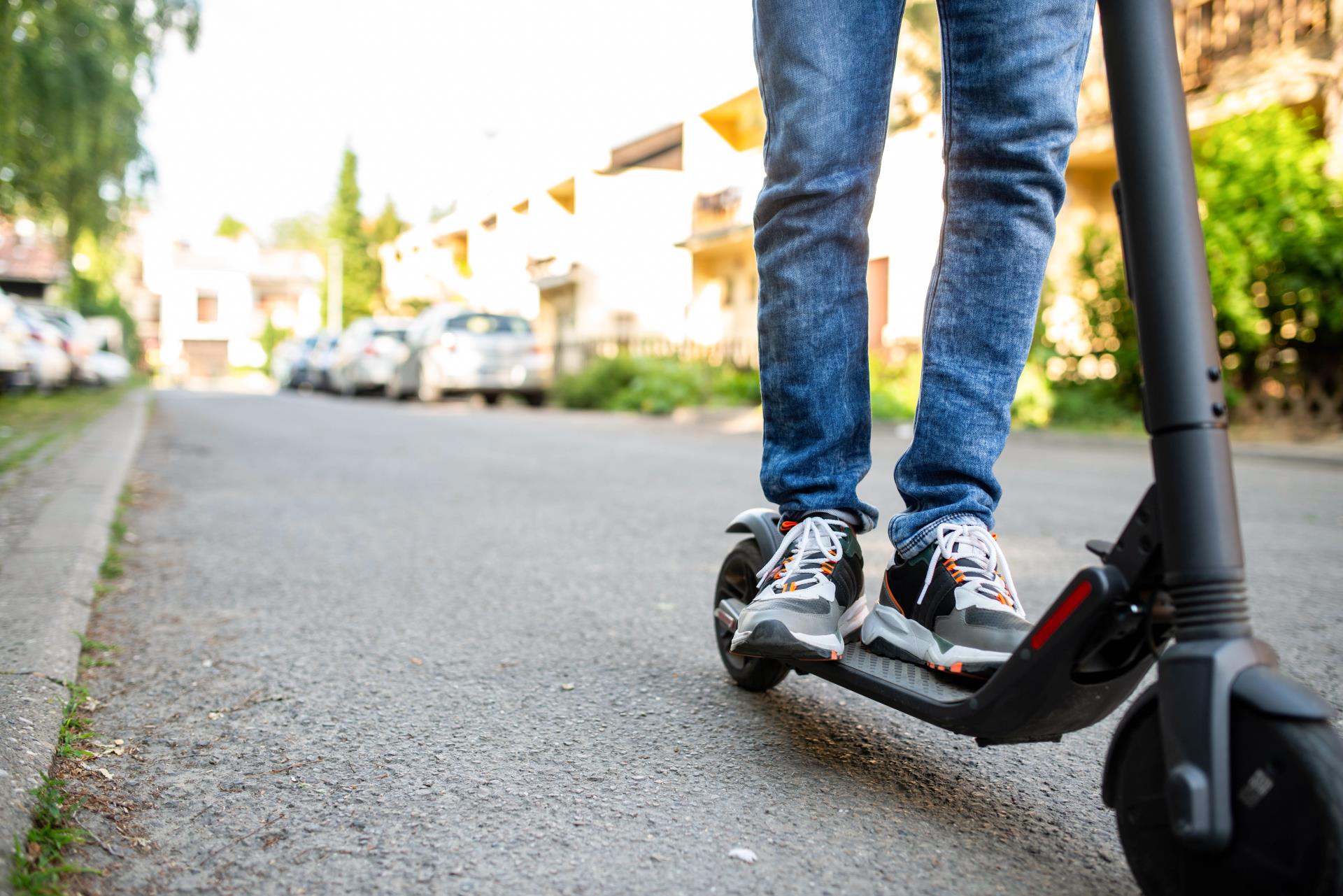 Close up of a person riding e-scooter on a residential street.