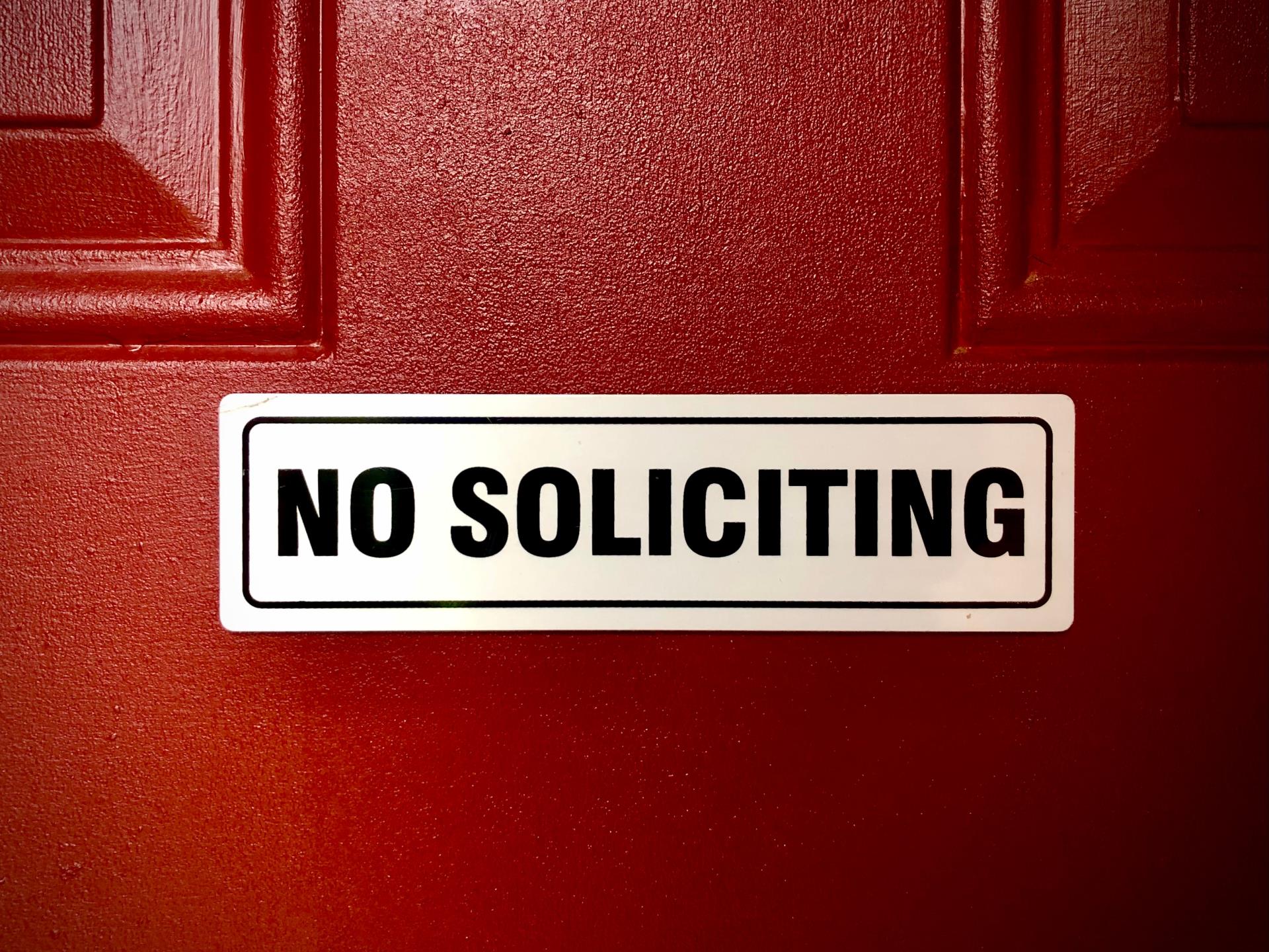 Sticker that says no soliciting on a front door.