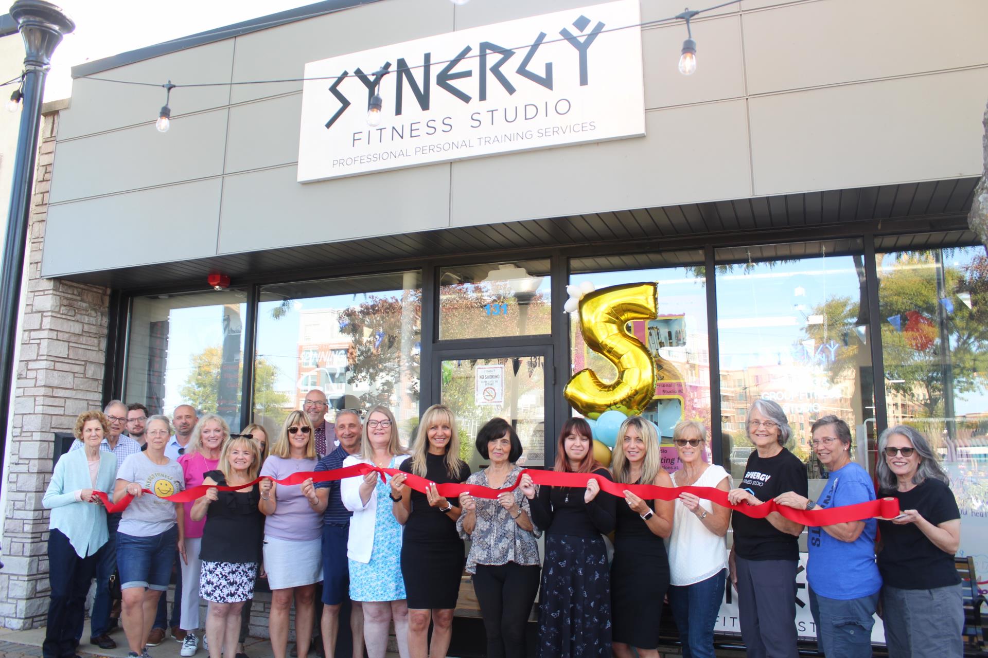 People holding red ribbon in front of Synergy Fitness