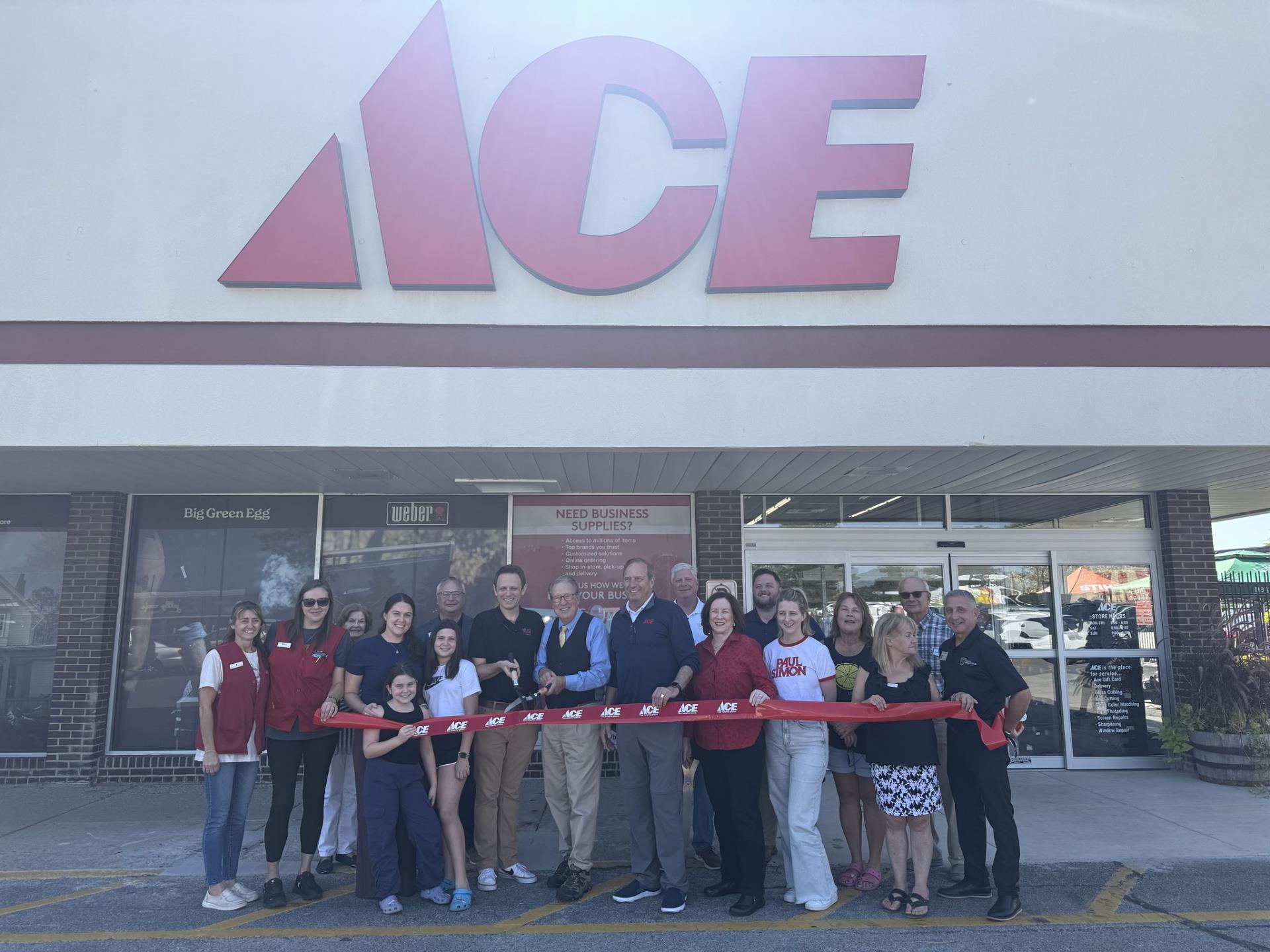 people holding ribbon in front of Ace Hardware